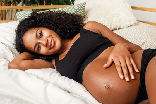 Femme enceinte dormant sur le côté avec un coussin de grossesse dans un lit douillet